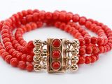 un gros plan sur un bracelet en perles rouges muni d'un fermoir doré