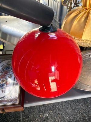 une boule rouge suspendue à une poignée noire posée sur une table