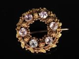 un gros plan sur une broche en or sertie de pierres roses