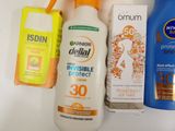 bottles of sunscreen, lotion, and lotion sprays on a white surface