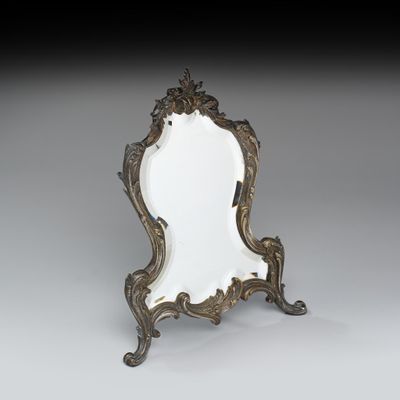 un miroir ancien avec un cadre doré, posé sur un pied