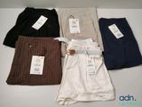 Quatre paires de pantalons de costume pour homme sont alignées sur une table