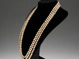 a pearl and gold necklace on a mannequin stand