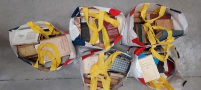 quatre sacs remplis de livres, entourés d'un ruban jaune, posés par terre