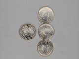 three silver coins sitting on top of each other on a white surface