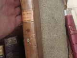 a person holding a book in front of a stack of books