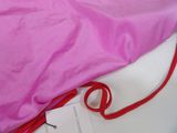purple bag with red string attached to it sitting on a white surface
