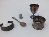 a silver cup, spoon, and other items on a white surface