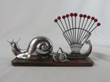 une sculpture en argent représentant un escargot et un éventail, posée sur un socle en bois