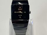 a black watch on a clear stand on a white surface