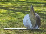 a metal sculpture on the ground in the grass