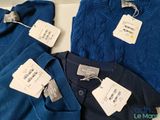 three pairs of blue sweaters with tags on them sitting on a table