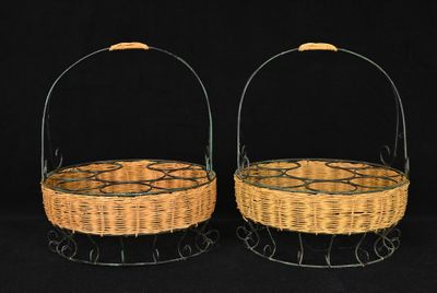 two wicker baskets with handles on a black background