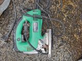 a green corded sander on the ground next to a pair of scissors