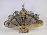 a brass fan with a decorative design on top of it