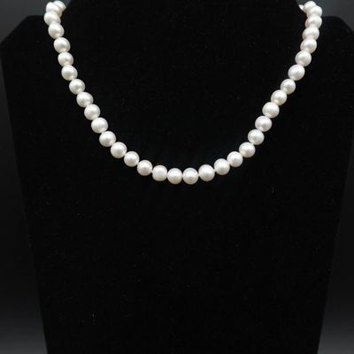 un collier de perles blanches sur un mannequin noir