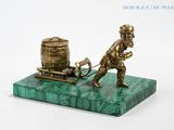 brass figurine of a man pulling a barrel on a plow