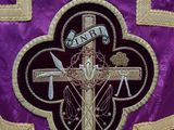 a close up of a purple and gold cross with a banner on it