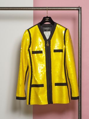 une veste jaune accrochée à un porte-vêtements devant un mur rose