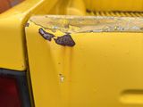 a yellow pick up truck parked in a parking lot