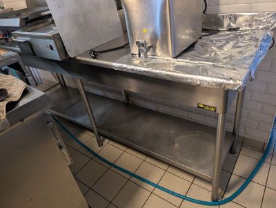 stainless steel counter top in a commercial kitchen with a blue hose attached to it