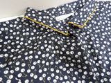 the shirt is blue with white flowers on it and yellow trim