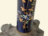 a blue vase with flowers on it sitting on a piece of wood
