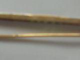 une barrette dorée posée sur une surface blanche