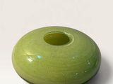 a green vase that is sitting on a white surface