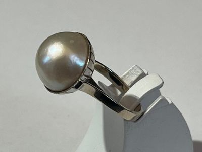 silver ring with a pearl on top of it on a white surface