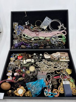 une boîte noire remplie de nombreux bijoux, posée sur une table