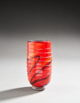a red vase sitting on a table with a shadow on the floor