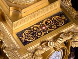 a gold and blue clock on a table with a black background