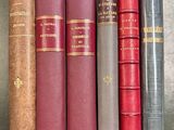 cinq vieux livres sont alignés les uns à côté des autres sur une étagère