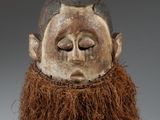 un gros plan d'un masque en bois orné d'une barbe