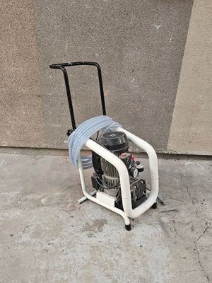 un petit compresseur d'air posé sur un chariot sur le trottoir