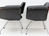 pair of black leather chairs with chrome legs against a white wall