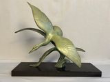 une sculpture en bronze représentant un oiseau, posée sur un socle noir