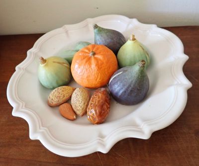 une assiette blanche posée sur une table, sur laquelle se trouvent des fruits et des noix