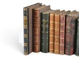 several old books are lined up in a row on a white surface