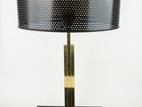 a black table lamp with a gold base and a black shade