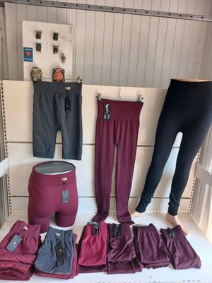 Plusieurs paires de leggings pour femmes sont exposées sur un banc blanc