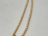 a close up of a pearl necklace on a white surface