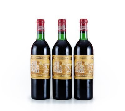 trois bouteilles de vin rouge posées l'une à côté de l'autre sur une surface blanche