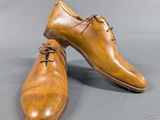 pair of brown leather shoes with laces on them on a gray surface
