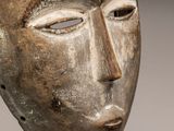 gros plan d'un masque en bois sur un support métallique