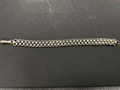 un gros plan d'un bracelet à chaîne argentée posé sur une surface noire