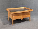 une image représentant une table en bois avec un plateau en verre posée sur une surface grise