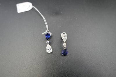a pair of sapphire and diamond earrings on a black surface