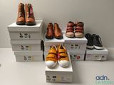 Plusieurs paires de chaussures sont empilées sur des cartons posés sur une table